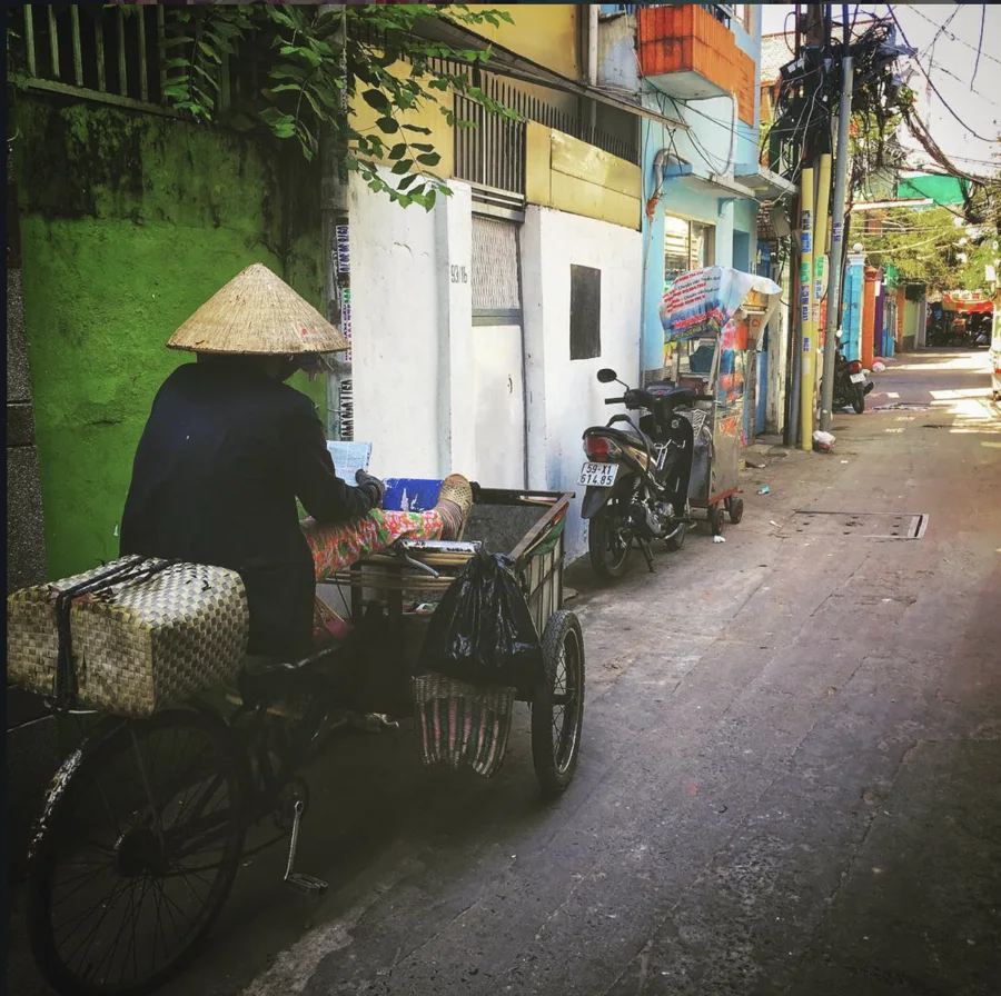 A street vendor with a cart beside a vivid green wall