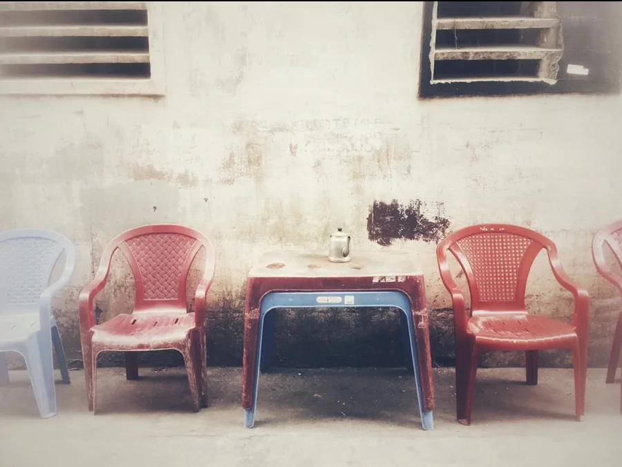 Red and blue plastic chairs around a small table and kettle