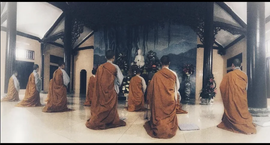 Orange-robed monks kneeling inside a temple