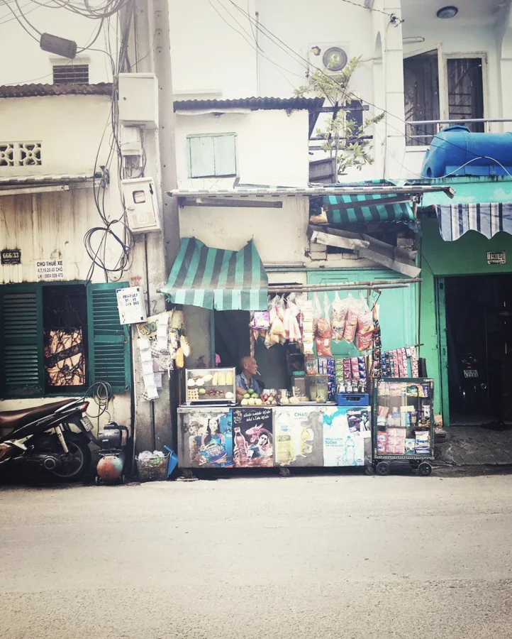 A small street-side stall under green striped awnings