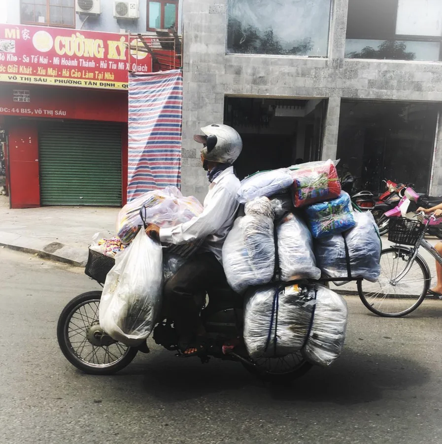 A motorbike carrying bundles along a busy street