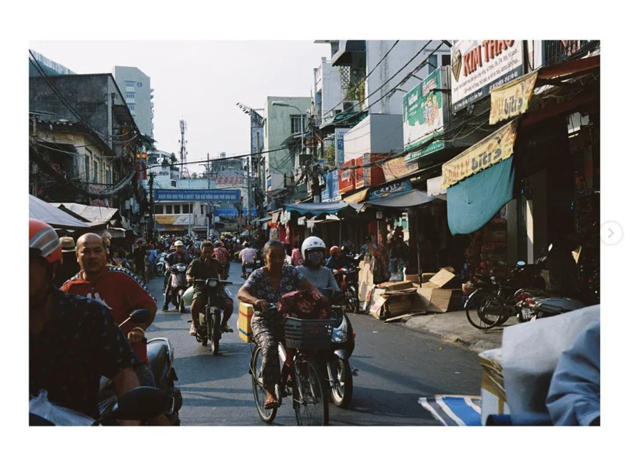 People on bicycles and motorbikes in a bustling market street