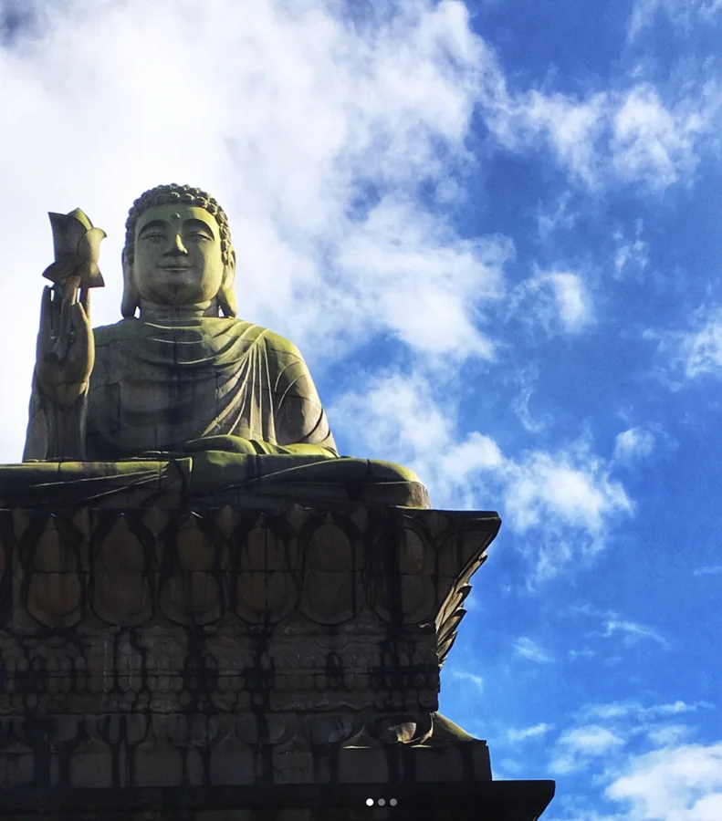 A seated Buddha statue beneath white clouds